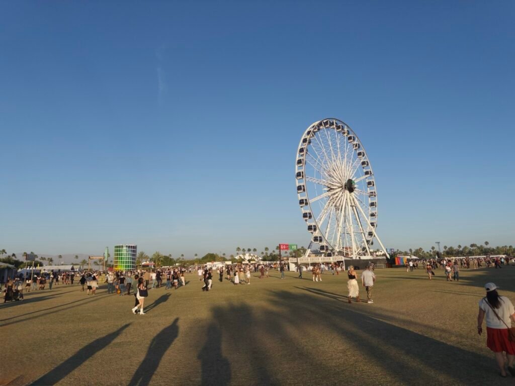 芝生が広がるStagecoachの会場。大きな白い観覧車とカラフルな塔のオブジェのまわりを、夕方の長い影を落としながら大勢の来場者が歩いている