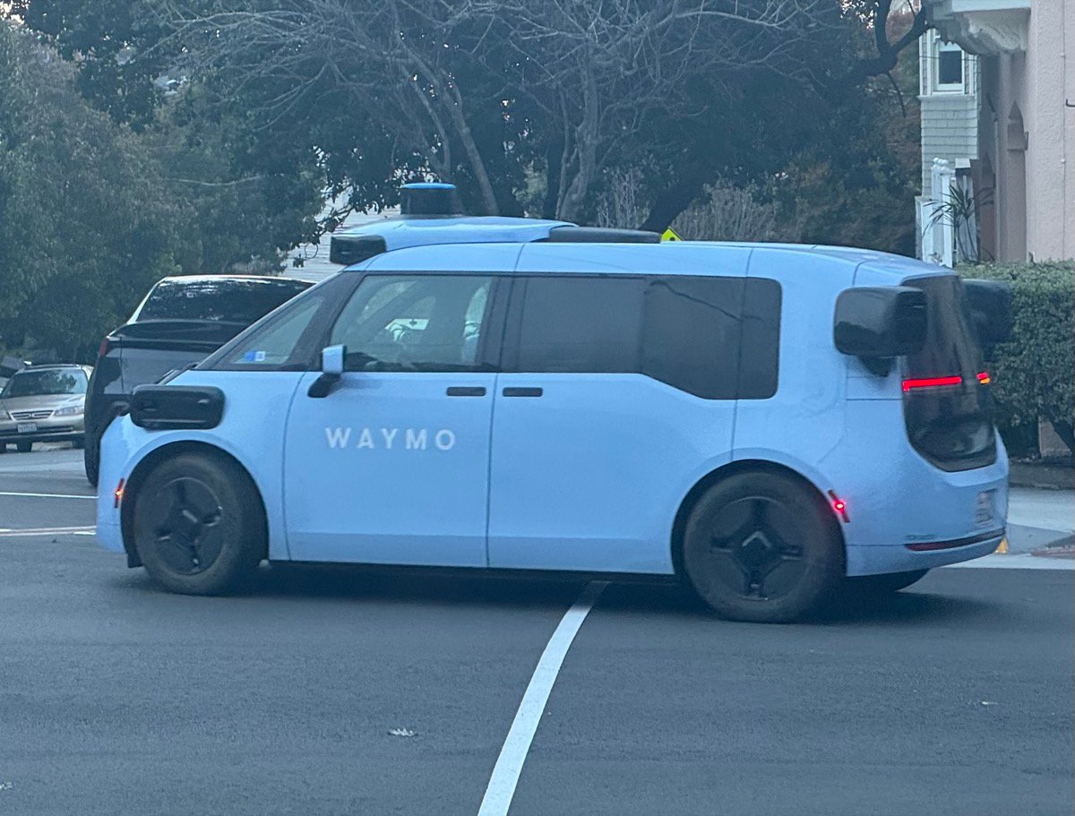車体に「WAYMO」ロゴが入った青い箱型の新型Waymo（第6世代Zeekr製）が、サンフランシスコの住宅街の路上に停車している。前後にスライドドア