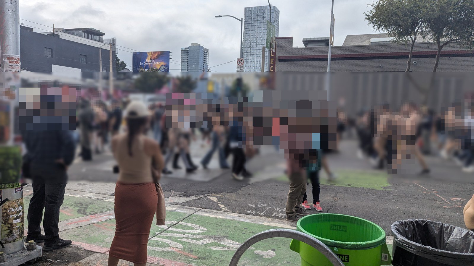 Folsom Street Fairの会場となったSOMAの交差点。レザーやハーネス姿の人で埋まった通りを、手前の人が眺めている。写っている人の顔はぼかし処理している。