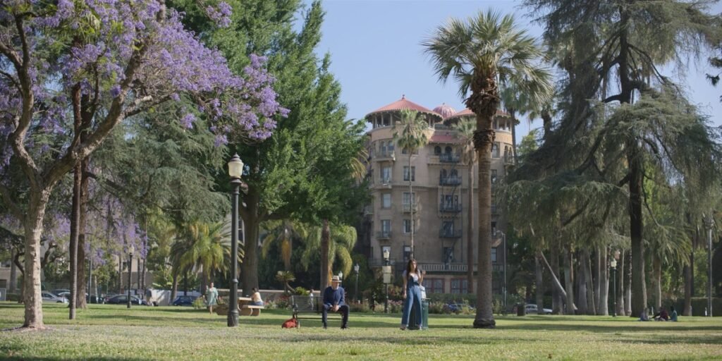 『Shrinking』劇中のワンシーン。Central Parkのベンチにポールが座り、横にアリスが立っている。奥にCastle Greenの建物が見える