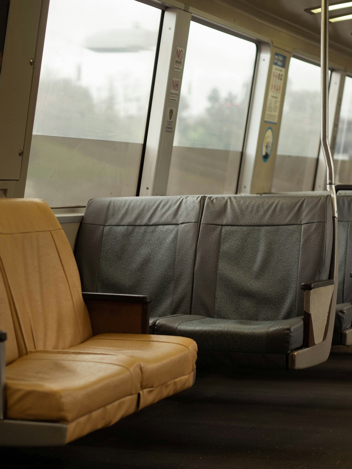 日中の自然光が差し込むBARTの車内。タン色のレザーとグレーの布地を組み合わせた座席が並び、人物はいない