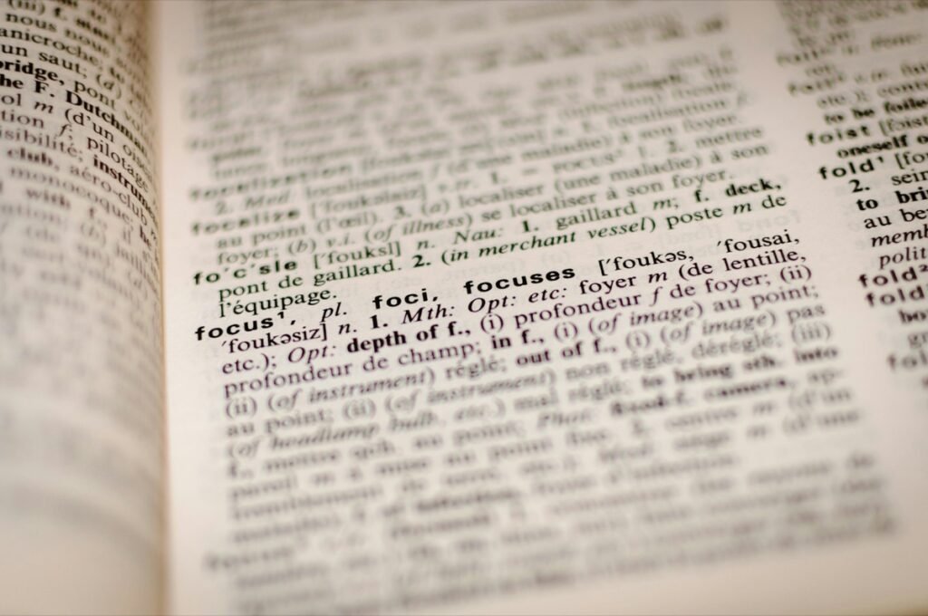 開いた英仏辞典のページのアップ。太字の見出し語「focus」の項目にピントが合い、周りの訳語はぼけている素材写真